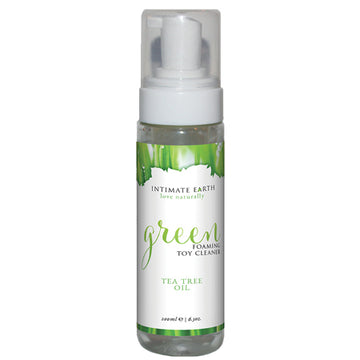 A clear plastic bottle with a white pump dispenser labeled 'Intimate Earth Green Foaming Toy Cleaner with Tea Tree Oil'. The label includes the product name and mentions it as a tea tree oil-infused cleaner.