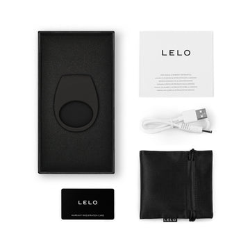 The image shows a black vibrating couples' ring, a USB charging cable, a black carrying case, and a card with the brand name LELO on it.